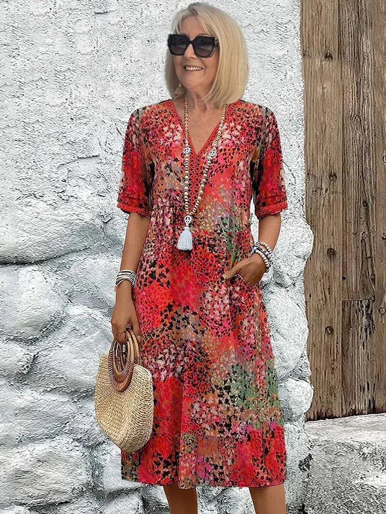Woman wearing a red abstract leopard print V-neck midi dress with half sleeves and a straw bag