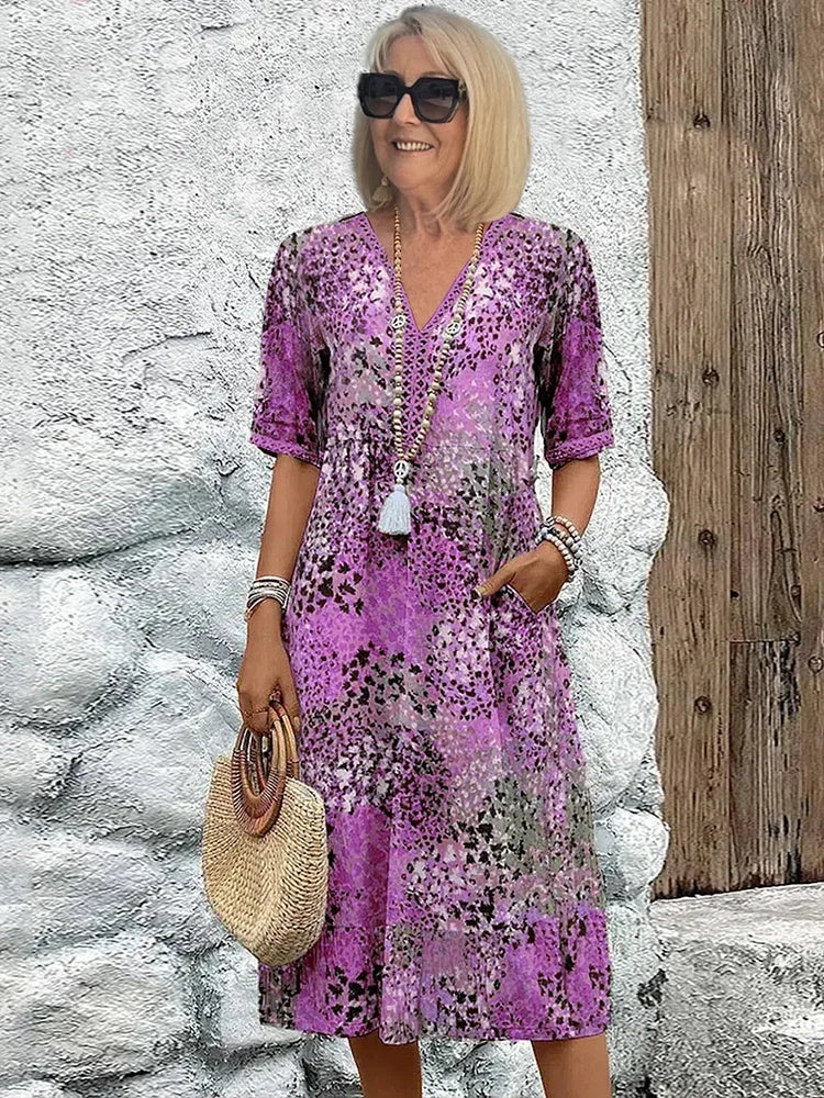 Purple mosaic print short-sleeve midi dress worn with layered beaded necklaces