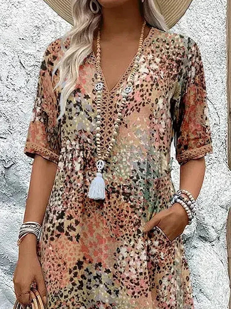 Close-up of the beige print V-neck neckline with crochet trim and beaded tassel necklace