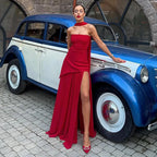 Three-quarter view of ivory strapless dress with sheer chiffon maxi skirt and satin neck tie, worn with silver heeled sandals