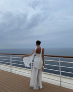 Back view of white one-shoulder draped gown showing the flowing chiffon neck tie trailing over the shoulder and open back