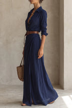 Side profile of the navy collared maxi dress with rolled sleeves, belted waist and woven tote bag