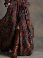 Detail of the flowing red and navy tartan skirt with front slit revealing brown knee-high boots