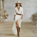 Model in white crinkle-cotton belted shirt dress with shawl collar, split skirt, wide-brim hat and brown knee-high boots