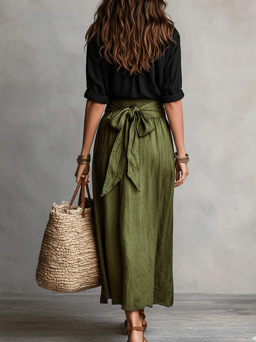 Back view showing the olive green skirt's tie-waist bow detail and the flowing maxi silhouette