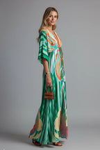 Three-quarter side view of the green printed maxi dress showing the wide kimono sleeve and ankle-grazing hem