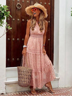 Blush pink tiered maxi dress with lace inserts and shimmering dot print, shown against a rustic wooden door backdrop.