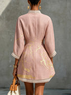 Back view of pink mini dress showing crochet lace collar trim, fitted waist seam and flared A-line hemline with gold print