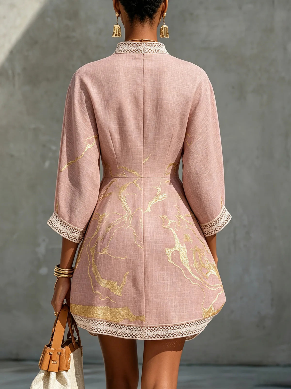 Back view of pink mini dress showing crochet lace collar trim, fitted waist seam and flared A-line hemline with gold print