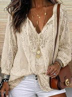 Beige lace blouse detail showing sheer floral pattern and loose sleeves, paired with a tan crossbody bag
