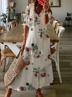 White maxi dress with red and green floral print, lantern sleeves and tiered flowing skirt
