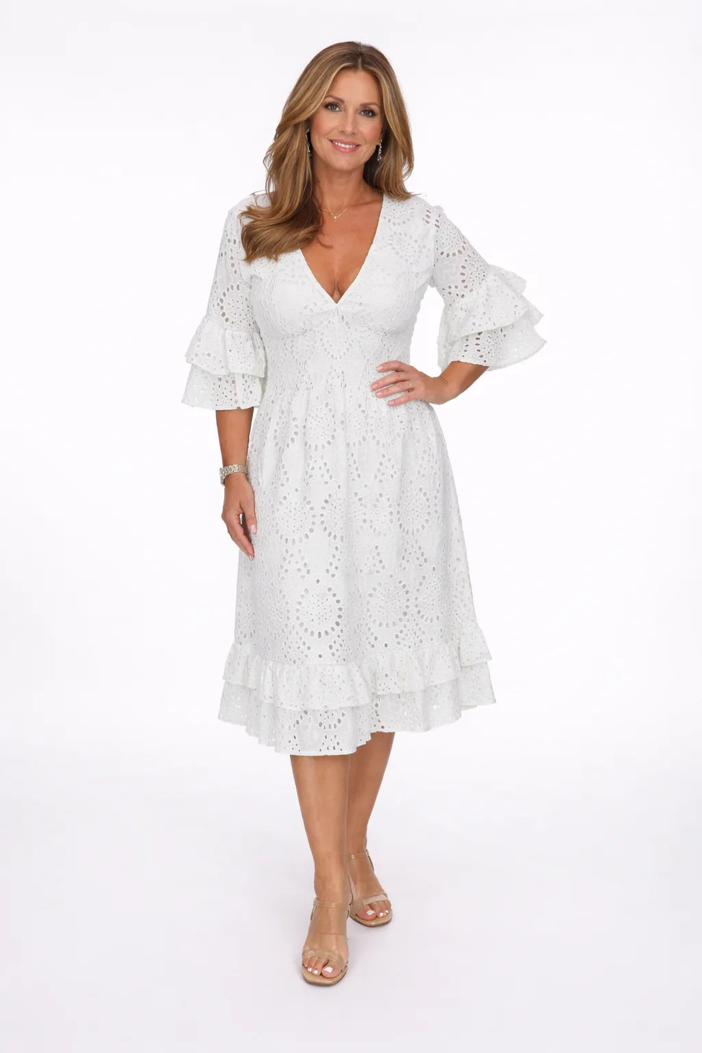 Front view of a woman in a white broderie anglaise midi dress with a deep V-neckline and ruffled bell sleeves