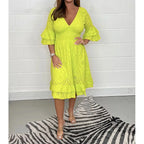Bright yellow eyelet cotton midi dress with ruffled trim and bell sleeves, paired with clear sandals