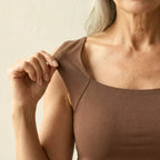 Close-up of the square neckline and raglan-style seam detail on the brown tank top