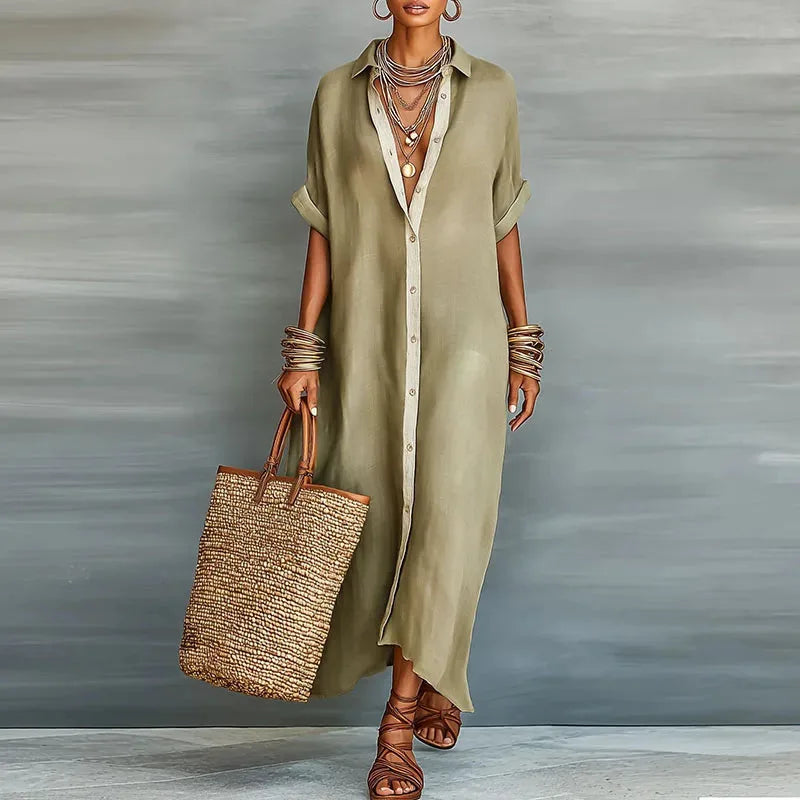 Woman in a khaki button-down maxi shirt dress with contrast placket, layered necklaces and a woven tote bag