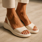 Close-up side view of cream platform slingback sandals worn with cropped beige trousers, showing the open toe and elastic strap.