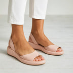 Blush pink sandals worn with white cropped trousers, front angle showing the smooth leather toe strap and platform sole.