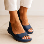 Close angle of navy sandals worn on bare feet, showing the open toe shape and slingback strap detail.