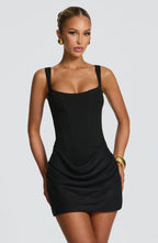 Front view of model wearing the black version of the mini dress with square neckline and wide straps