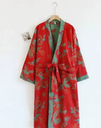 Red kimono robe featuring a dragon and phoenix print with contrasting green lapel, hung beside a framed photo