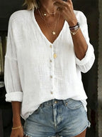 White textured cotton linen blouse with V-neck, button front and relaxed long sleeves, close-up front view.