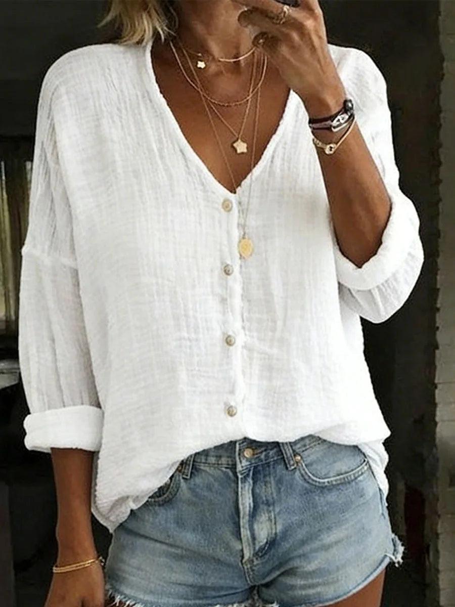 White textured cotton linen blouse with V-neck, button front and relaxed long sleeves, close-up front view.