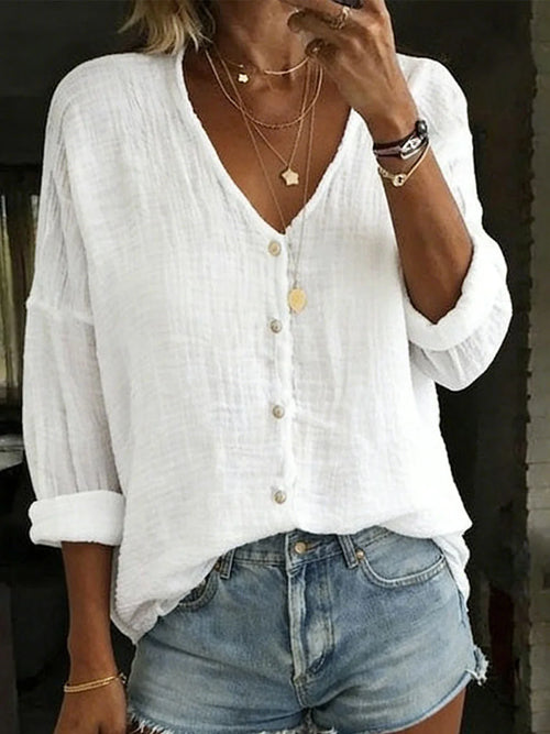 White textured cotton linen blouse with V-neck, button front and relaxed long sleeves, close-up front view.