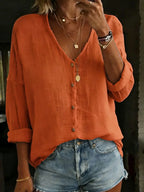 Burnt orange cotton linen blouse with wooden-look buttons and relaxed long sleeves rolled at the cuff.