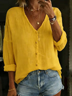 Mustard yellow cotton linen blouse with V-neck button front, styled with layered necklaces and denim shorts.