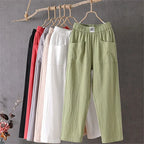 Front view of relaxed-fit cotton linen pants in sage green with patch pockets hanging on a wooden hanger