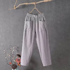 Grey cotton linen pants hanging against a rustic backdrop, showing the relaxed straight-leg silhouette