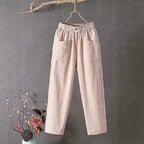 Pale pink cotton linen pants hanging with visible fabric texture and roomy patch pockets