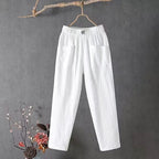 White cotton linen pants hanging flat, showing the clean straight-leg cut and elastic waist tag