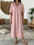 Front view of model wearing a dusty pink cotton linen polo dress with button placket and collar in a boho living room