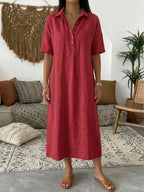 Red polo dress with button placket and classic collar styled with tan woven sandals indoors