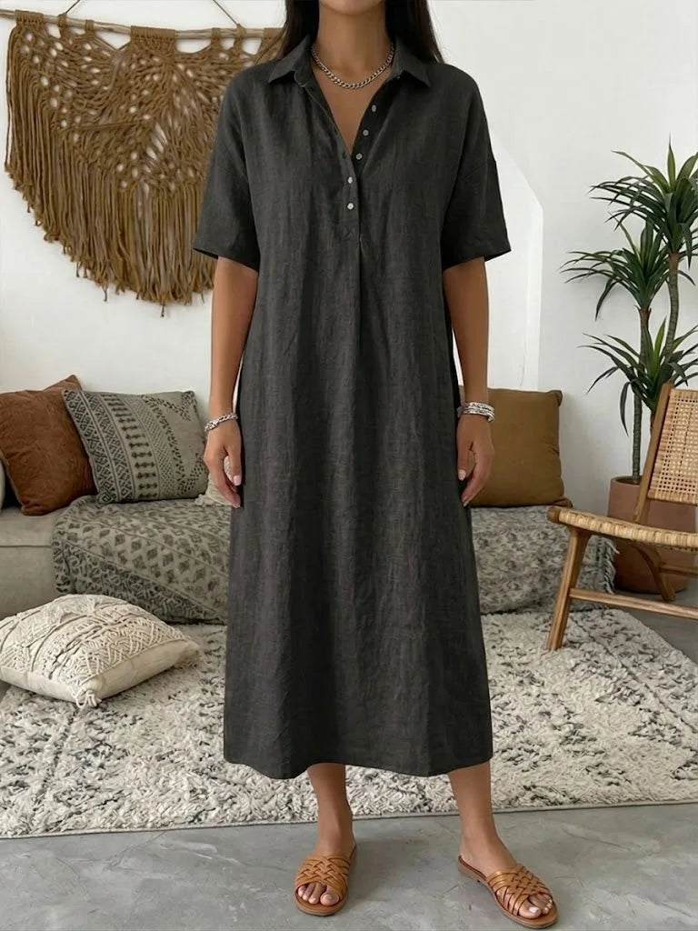 Charcoal black polo dress with relaxed drape and short sleeves shown against a boho macrame wall hanging