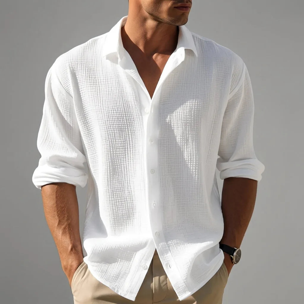 Close-up front view of a man wearing a white textured cotton-linen shirt, unbuttoned collar and rolled sleeves, paired with beige pants