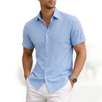Man wearing a light blue short-sleeve button shirt in a soft woven cotton, collar open at the neck