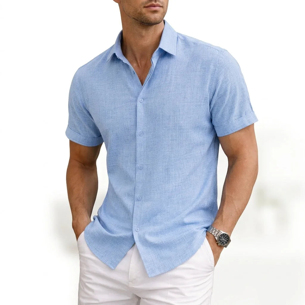Man wearing a light blue short-sleeve button shirt in a soft woven cotton, collar open at the neck