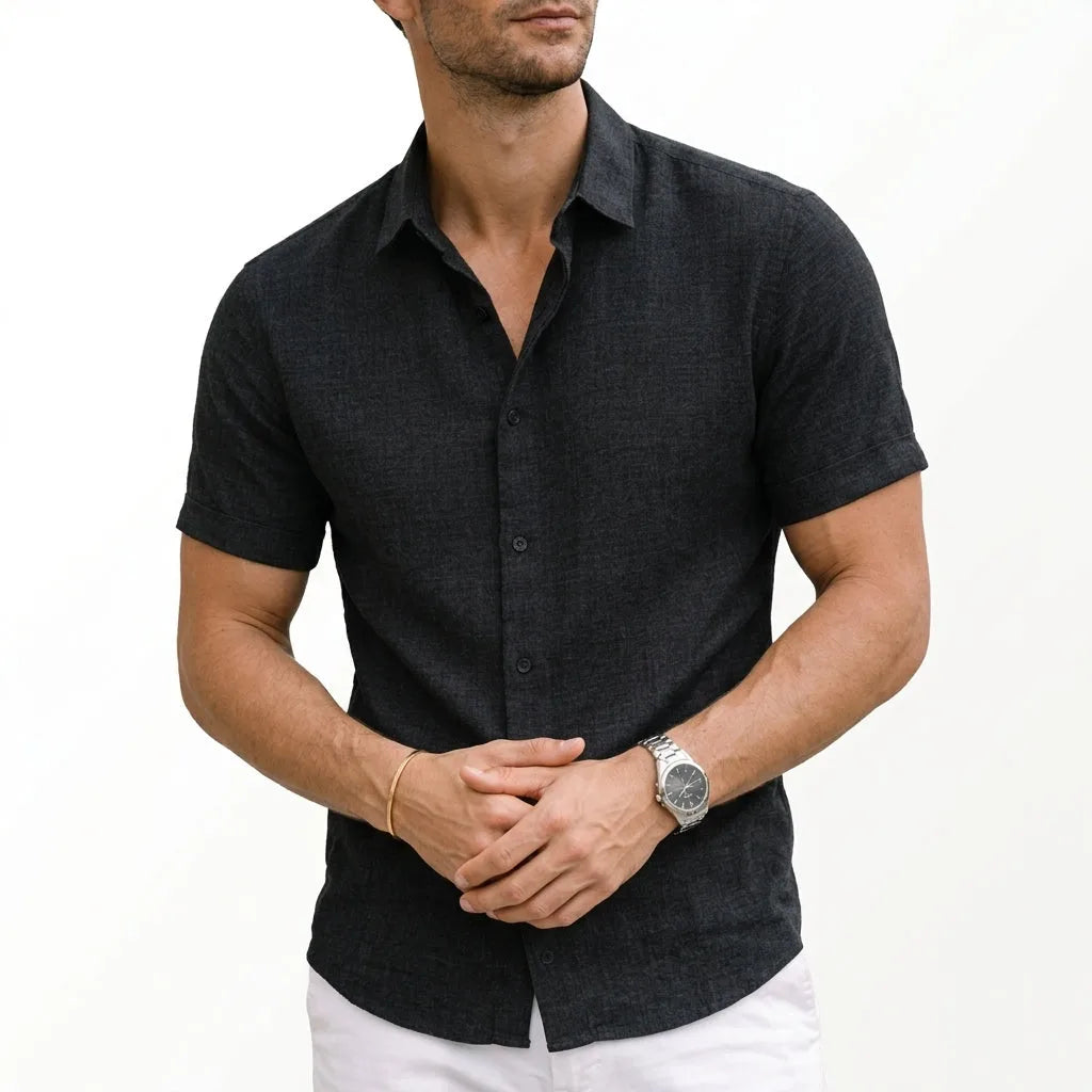 Charcoal black woven shirt with short sleeves, buttoned to the collar, hands clasped at the front