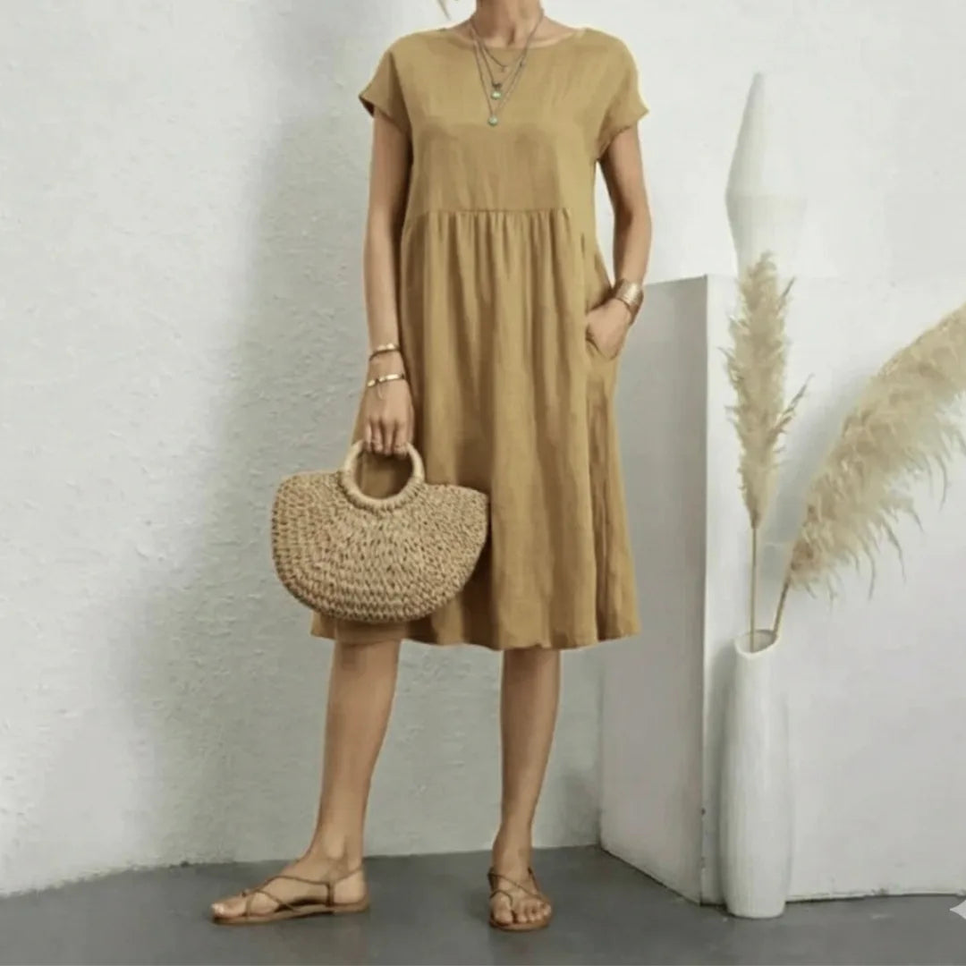 Front view highlighting the round neckline, dropped shoulders and smocked waist seam of the dress