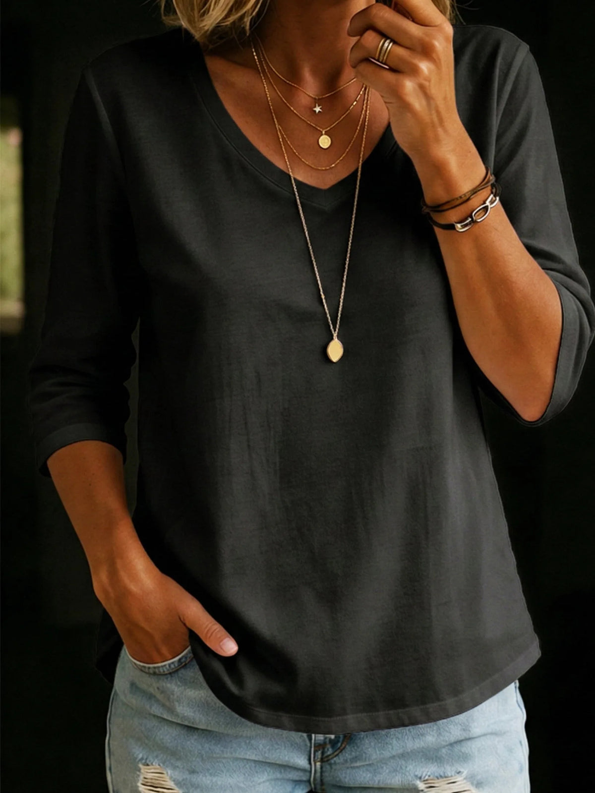 Charcoal black V-neck T-shirt with relaxed three-quarter sleeves and a curved hem, paired with a pendant necklace