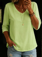 Soft lime green V-neck T-shirt with three-quarter sleeves and a curved dropped hem, worn with ripped light-wash denim