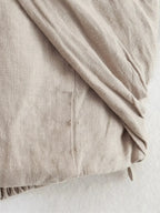 Macro shot of the beige linen-blend fabric showing its woven texture and soft drape