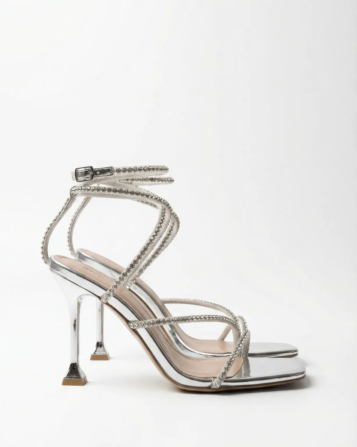 Side profile of a silver mirror-finish stiletto sandal with crystal straps winding around the ankle and a sculpted heel.