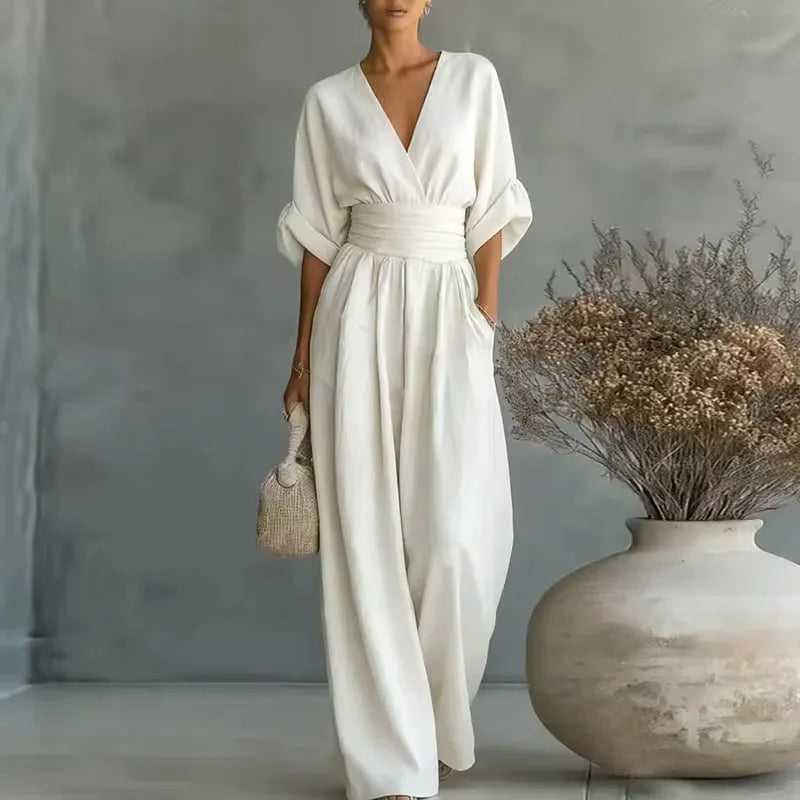 Woman wearing a white V-neck wide-leg jumpsuit with wrap bodice, cinched waistband and 3/4 cuffed sleeves