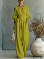 Lime green V-neck jumpsuit with structured waistband, wide flowing trouser legs and rolled 3/4 sleeves