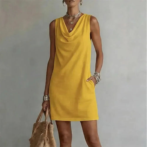 Front view of a sleeveless yellow mini dress with a soft cowl neckline, shown with a woven tote bag