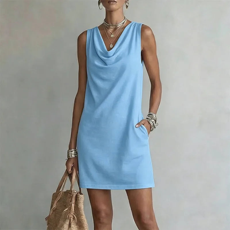 Sky blue sleeveless mini dress with a relaxed draped neckline and hand resting in the side pocket