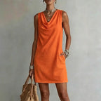 Close view of an orange sleeveless mini dress highlighting the soft fabric drape at the neckline